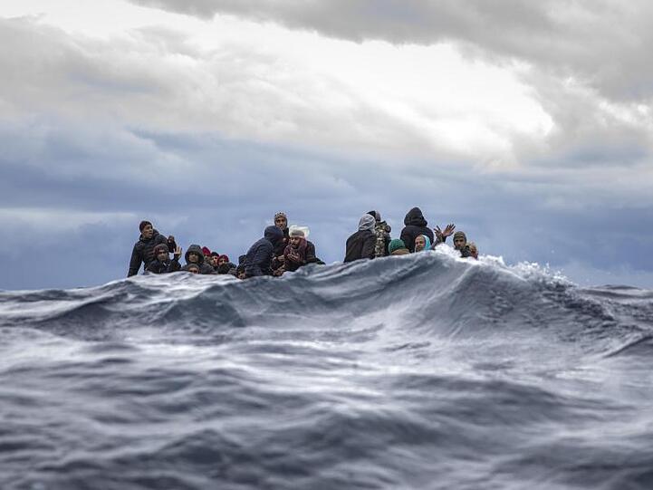 Rettung in letzter Sekunde: Männer aus Marokko und Bangladesch sitzen in einem überfüllten Holzboot vor der libyschen Küste, als sich ihnen Hilfsarbeiter der spanischen Hilfsorganisation "Open Arms" nähern.