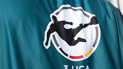 Ein Mitarbeiter der Fernsehproduktion trägt ein Leibchen mit dem Logo der 3. Liga.