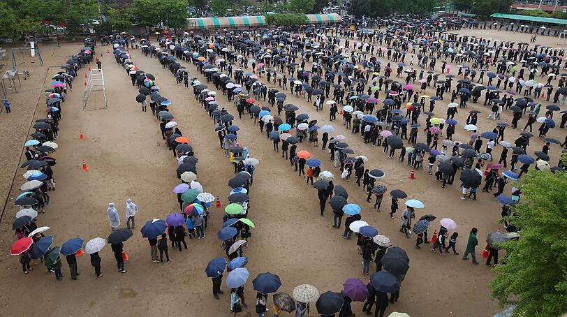 Olympische Gedenkstätte in Ansan: Eine lange Schlange von trauernden Menschen wartet im Nieselregen vor einem Altar für die Opfer der gesunkenen Fähre vor Südkorea.