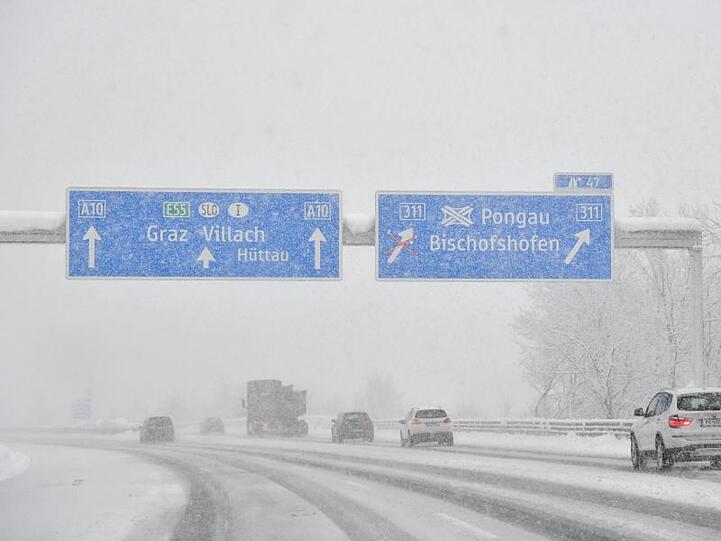 Autos sind bei Salzburg auf der verschneiten Autobahn unterwegs.