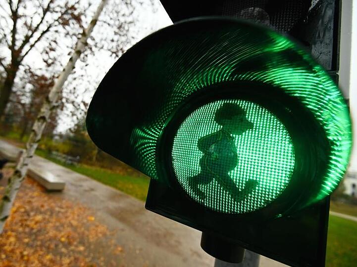 Auf der grünen Leuchtfläche einer Ampel, die neben Bäumen in der Natur steht, erscheint das Sams. Foto: Nicolas Armer/dpa
