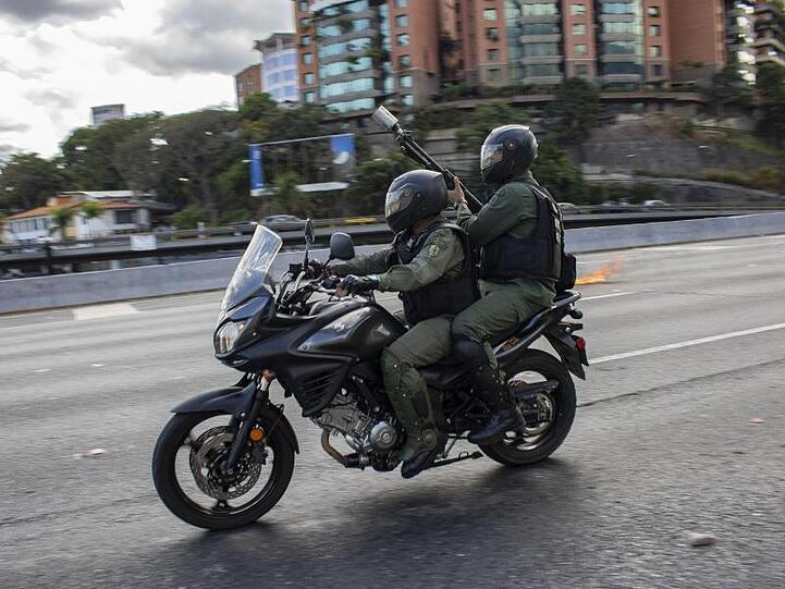 Angehörige der Nationalgarde fahren in Caracas auf einem Motorrad, um Demonstranten zu vertreiben.