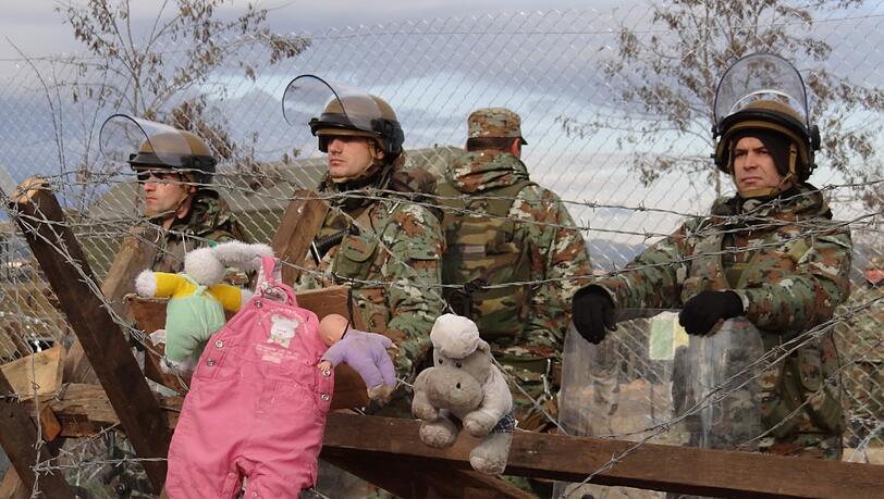 Mazedonische Soldaten bewachen die Grenze. Auf der griechischen Seite haben Flüchtlinge Stofftiere an den Zaun gehängt. Mazedonische Soldaten bewachen die Grenze. Auf der griechischen Seite haben Flüchtlinge Stofftiere an den Zaun gehängt.