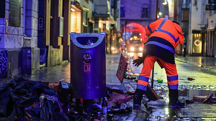 Wo gefeiert wird, fällt Müll an: Mitarbeiter der Straßenreinigung fegen in der Nacht in Köln den Abfall zusammen.