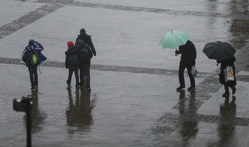 Passanten laufen am 30.03.2015 in Hamburg durch einen Regenschauer über den Rathausmarkt.