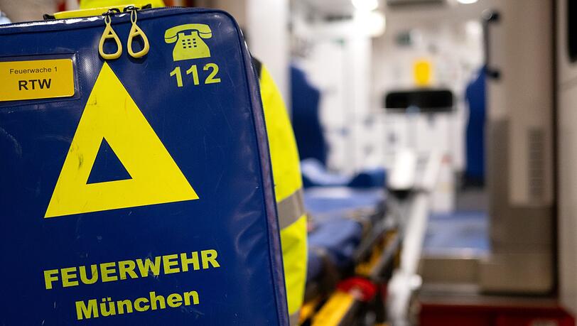 Feuerwehrleute der Berufsfeuerwehr München bereiten an der Feuerwache 1 in der Fahrzeughalle einen Krankenwagen für einen Einsatz vor.