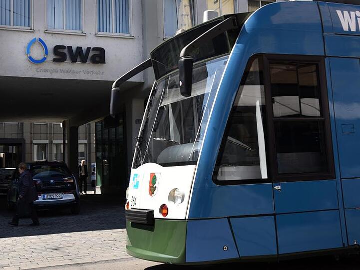Vor der Zentrale der Augsburger Stadtwerke steht eine Straßenbahn.