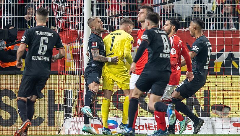 Finn Dahmen (3.v.l.), Torwart vom FC Augsburg, jubelt, nachdem er den Elfmeter von Berlins Robin Knoche (4v.r.) gehalten hat.