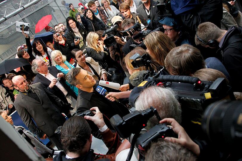 Weltstar im Fan-Gewusel: Robbie Williams verteilte Autogramme vor dem Mathäser-Kino.