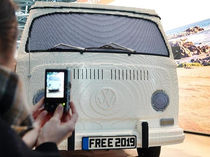 Eine Frau fotografiert bei der Reise- und Freizeitmesse free einen VW-Bus aus Legosteinen. Foto: Katharina Redanz
