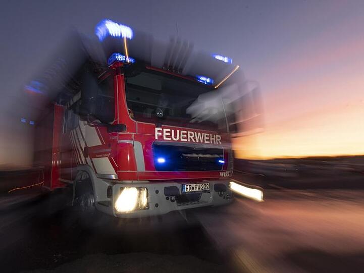 Ein Feuerwehrfahrzeug steht mit eingeschaltetem Blaulicht auf einer Straße. Foto: Patrick Seeger/dpa/Archivbild