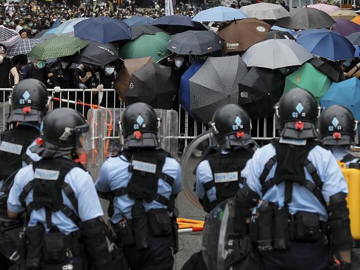 Polizisten stehen in der Nähe des Legislativrates Demonstranten gegenüber.
