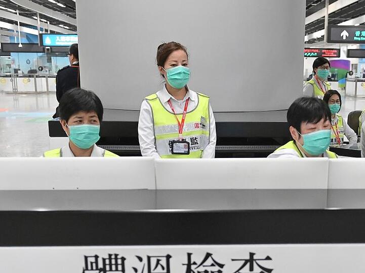 Vorsorge in Hongkong: Mitarbeiter des Gesundheitswesens untersuchen am Bahnhof West Kowloon Station Reisende auf ihren Gesundheitszustand.