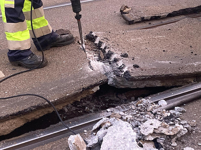 Mit einem Presslufthammer tragen MVG-Mitarbeitende die kaputte Straße ab.