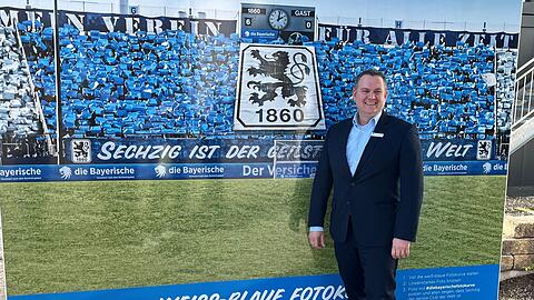 Oliver Mueller, neuer Geschäftsführer des TSV 1860 München, steht vor eine Fotowand.