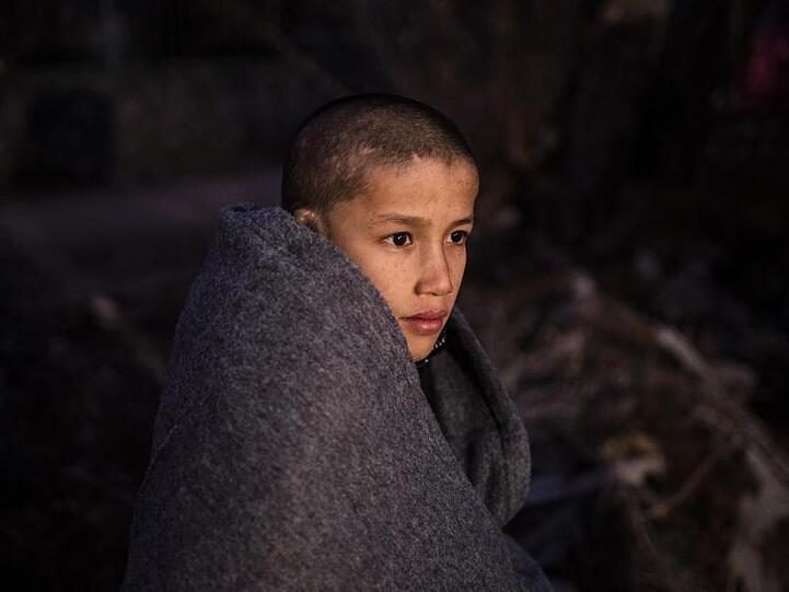 Ein Junge sitzt in Decken eingewickelt in der Nähe eines Dorfes auf Lesbos. Mehrere EU-Staaten, unter ihnen Deutschland, wollen Griechenland mindestens 1600 unbegleitete minderjährige Migranten und andere Flüchtlinge abnehmen.