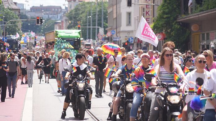Mittendrin, statt nur dabei: Münchens OB Dieter Reiter ganz leger in Jeans, schwarzem T-Shirt, Sneakers und regenbogenfarbiger Blümchenkette. Rechts neben ihm Dominik Krause.