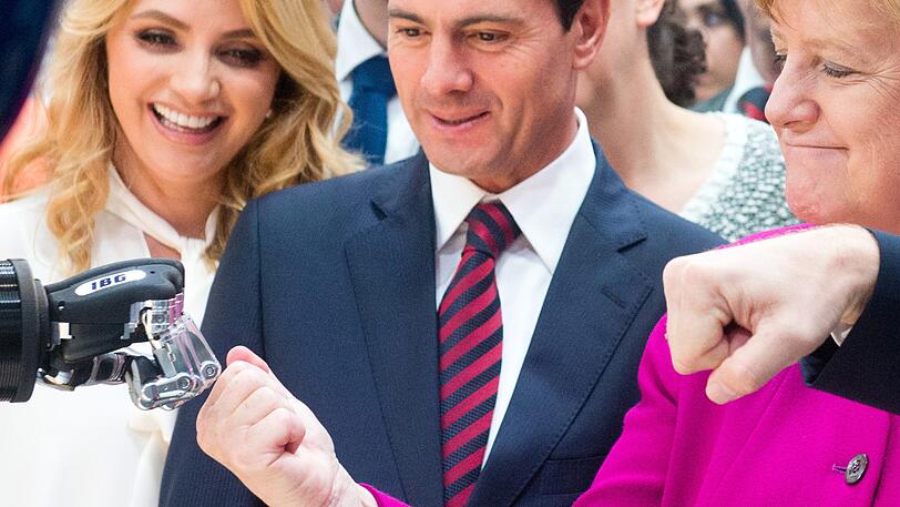 Bundeskanzlerin Angela Merkel (r, CDU) und Enrique Pena Nieto, Präsident des Gastlandes Mexiko, mit seiner Frau Rivera de Peno gehen bei der Hannover Messe 2018 am Stand von IGB Automation auf Tuchfühlung mit einer Roboterhand.
