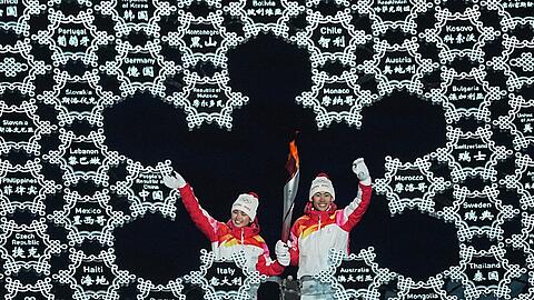 Chinas Zhao Jiawen (r) und Yilamujiang Dinigeer haben das olympische Feuer für die Winterspiele in Peking entzündet.