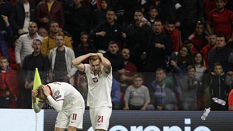 Polen Spieler schützen sich vor den Flaschenwürfen der albanischen Anhänger.