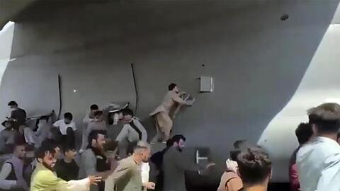 Menschen laufen auf dem Rollfeld des Flughafens Kabul neben einer Boeing C-17 der United States Air Force und versuchen, sich an die Maschine zu klammern.