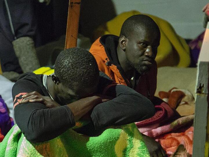 Migranten sitzen an Deck des unter deutscher Flagge fahrenden Schiffes "Alan Kurdi".