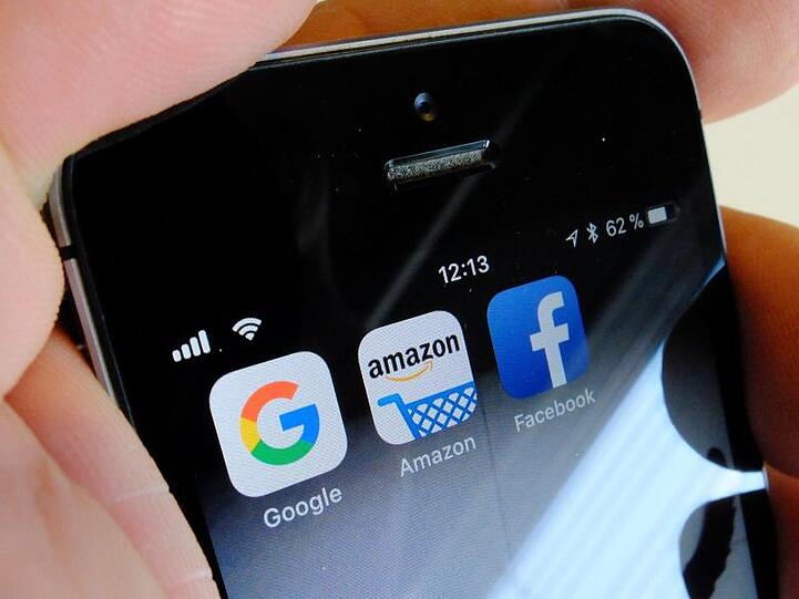 Logos der US-Internetkonzerne Google, Amazon und Facebook sind auf dem Display eines iPhones zu sehen.