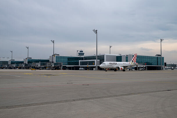 Ein Flugzeug f&auml;hrt am Au&szlig;enbereich des Erweiterungsbau des Terminals 1 am M&uuml;nchner Flughafen vorbei. Der Neubau erm&ouml;glicht Kapazit&auml;ten f&uuml;r bis zu sechs Millionen Passagiere pro Jahr. Eine dritte Startbahn wird derzeit aber nicht gebaut.