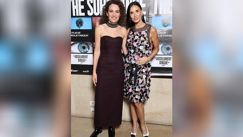 Bl&uuml;ten, wohin das Auge reicht: Demi Moore (r.) strahlt auf dem roten Teppich in Paris an der Seite von Filmemacherin Coralie Fargeat.
