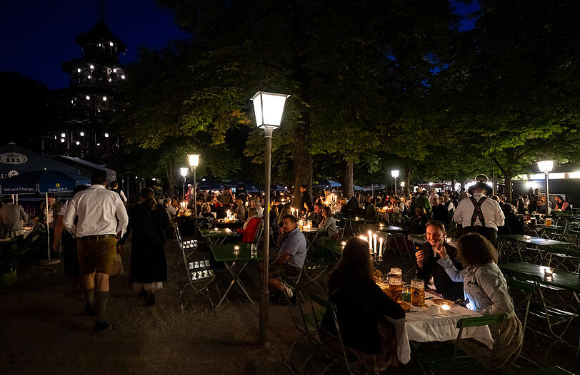 Zahlreiche Besucher des traditionellen Kocherlball sitzen am Chinesischen Turm im Englischen Garten an Biertischen.