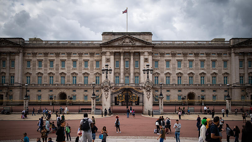 Touristen stehen vor den Toren des Buckingham Palasts (Archivbild).
