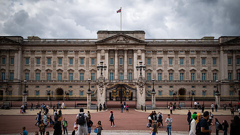 Touristen stehen vor den Toren des Buckingham Palasts (Archivbild).