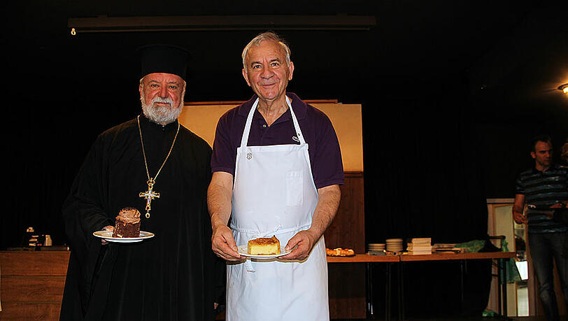 Stylianos Klastos (r.) mit seinem Lieblingsgebäck „Galaktompoureko“ und daneben der Erzpriester Apostolos Malamoussis. Stylianos Klastos (r.) mit seinem Lieblingsgebäck „Galaktompoureko“ und daneben der Erzpriester Apostolos Malamoussis.