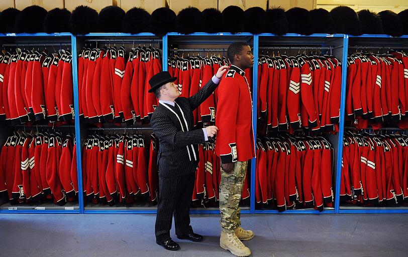 Ein Schneider passt einem Soldaten die Paradeuniform an.