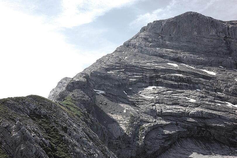 Der Grat verengt sich. Der Felsen knapp vor dem Gipfelaufbau wird nicht überstiegen, sondern rechts umgangen. Dafür geht es kurz nach unten und über eine schottrige Rinne mühsam wieder nach oben.