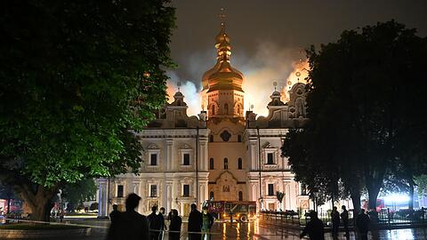 Flammen z&uuml;ngeln aus dem Dach unter den vergoldeten Kuppeln der Mari&auml;-Entschlafens-Kathedrale.