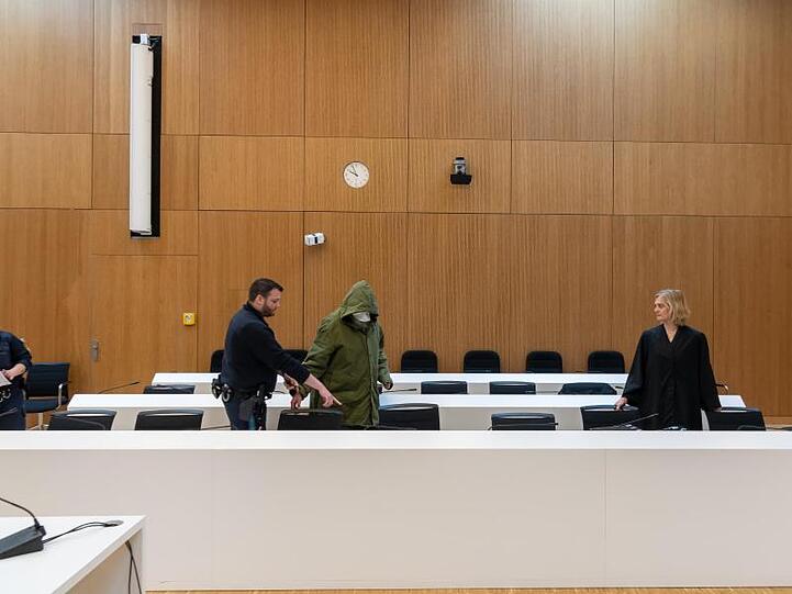 Ein 56 Jahre alter, wegen sexuellen Kindesmissbrauchs, angeklagter Mann (M) wird zu Prozessbeginn am Landgericht München II in den Saal geführt. Foto: Peter Kneffel/dpa