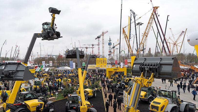 Besucher laufen über das Messegelände der Bauma. Die Bauma findet alle drei Jahre statt und ist das weltgrößte Branchentreffen der Baumaschinenhersteller. Besucher laufen über das Messegelände der Bauma. Die Bauma findet alle drei Jahre statt und ist das weltgrößte Branchentreffen der Baumaschinenhersteller.