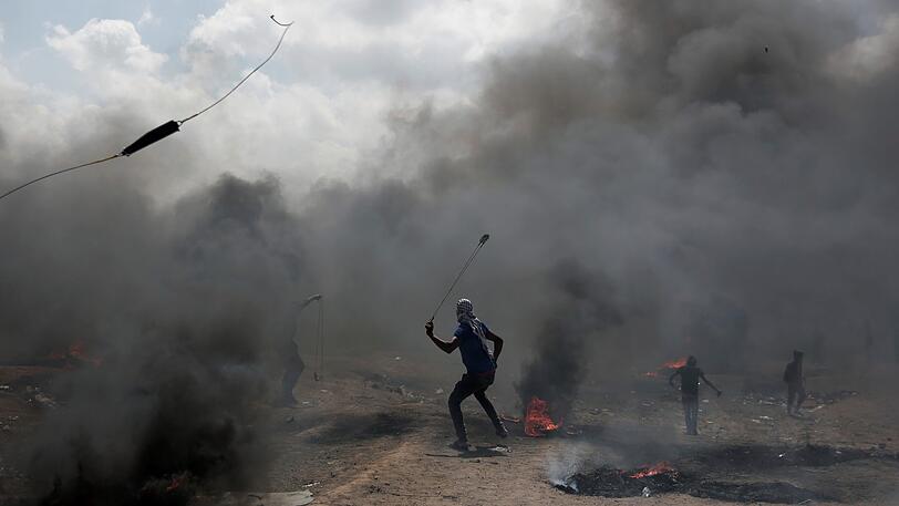 Palästinenser schleudern Steine gegen israelischen Truppen an der Grenze zwischen Gazastreifen und Israel bei Protesten für die Rückkehr in ihre Heimat.