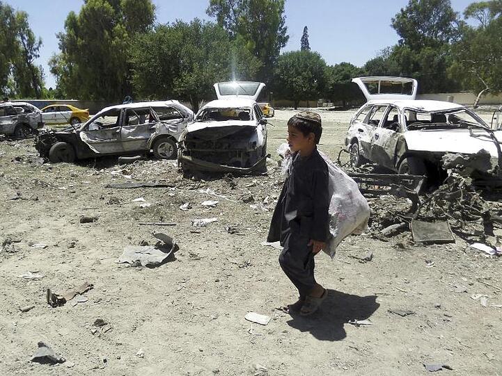 Alltag in Afghanistan: Ein kleiner Junge geht nach einem Selbstmordanschlag an Autowracks vorbei.