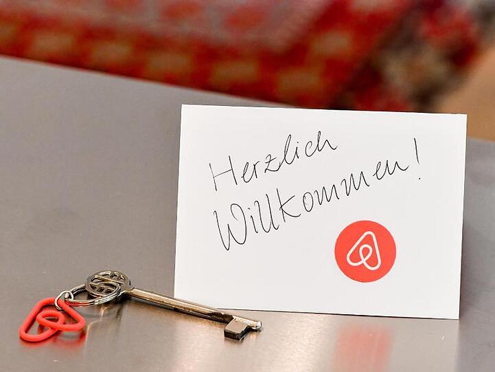 Ein Schlüssel mit einem Airbnb-Anhäger und eine Herzlich-Willkommen-Karte in der Wohnung eines Airbnb-Gastgebers.