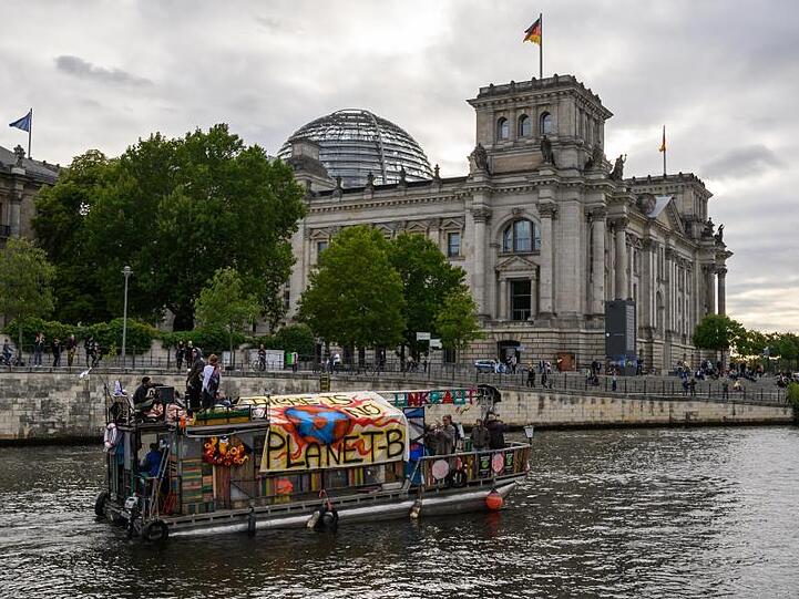 Demonstranten fahren mit einem Boot am Berliner Reichstagsgebäude vorbei. Das Klimapaket der Bundesregierung wird von Opposition, Umweltschützern und Wirtschaftsverbänden weiter scharf kritisiert.