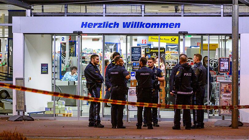 Einsatzkräfte der Polizei stehen in Abensberg auf einem Parkplatz neben einem Supermarkt, vor dem Schüsse gefallen sind.