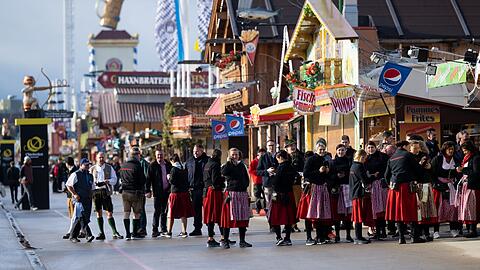 Bedienungen warten vor einem Festzelt auf die ersten Wiesnbesucher.