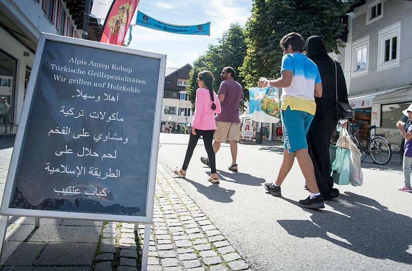 Eine Werbetafel in der Fußgängerzone von Garmisch preist auf Arabisch Grillspezialitäten an. Foto: Peter Kneffel