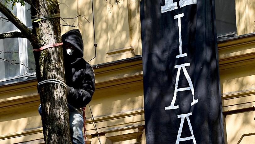 Ein vermummter Demonstrant ist vor dem besetzten Haus auf einen Baum geklettert. Ein vermummter Demonstrant ist vor dem besetzten Haus auf einen Baum geklettert.