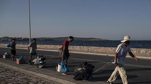 Flüchtlinge auf Lesbos ziehen ihre Habseligkeiten hinter sich her.