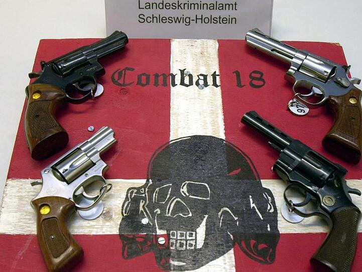 Sichergestellte Waffen und ein Schild der Neonazi-Gruppe "Combat 18" im schleswig-holsteinischen Landeskriminalamt.