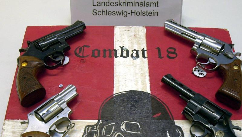 Sichergestellte Waffen und ein Schild der Neonazi-Gruppe "Combat 18" im schleswig-holsteinischen Landeskriminalamt. Sichergestellte Waffen und ein Schild der Neonazi-Gruppe "Combat 18" im schleswig-holsteinischen Landeskriminalamt.