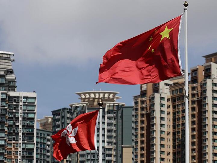 Die Flagge der Sonderverwaltungszone Hongkong (l) und die Flagge der Volksrepublik China wehen vor Wolkenkratzern.(Symbolbild).